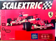 Cargar imagen en el visor de la galería,  Circuito de Scalextric con 2 coches F1 Ferrari F2004. El circuito tiene forma de 8 prolongado con unas dimensiones de 2.93 m x 1.38 m y un total de 6.49 m de recorrido. El estuche incluye un trainer 2 para poder competir contra la máquina cuando sólo un hay 1 corredor 