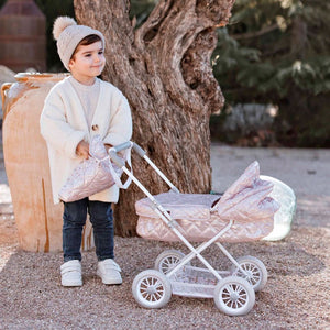 Coche de paseo con capota de la colección FANTASY. Plegable y con capazo extraíble. Este carrito en tela rosa acolchada brillante y motivos florales es perfecto para salir a pasear por el parque con tu muñeca preferida. Incluye bolso a juego donde poder guardar todos los accesorios de los muñecos. La altura del manillar es de 55 cm. 